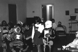 Several children in Halloween costumes with adults