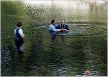 Elder Clarke Lee baptizes Kathy Lee in Satilla River as Julie Lee looks on