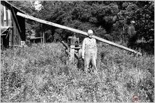 Inez Paulk posing in front of his old stick tobacco barn and mule sweep for grinding cane;  Paulk is mentor and father-in-law to Puddin' Creek's owner